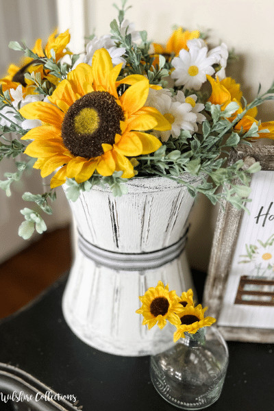 diy dollar tree craft with two painted flower pots stacked and containg a sunflower arrangement