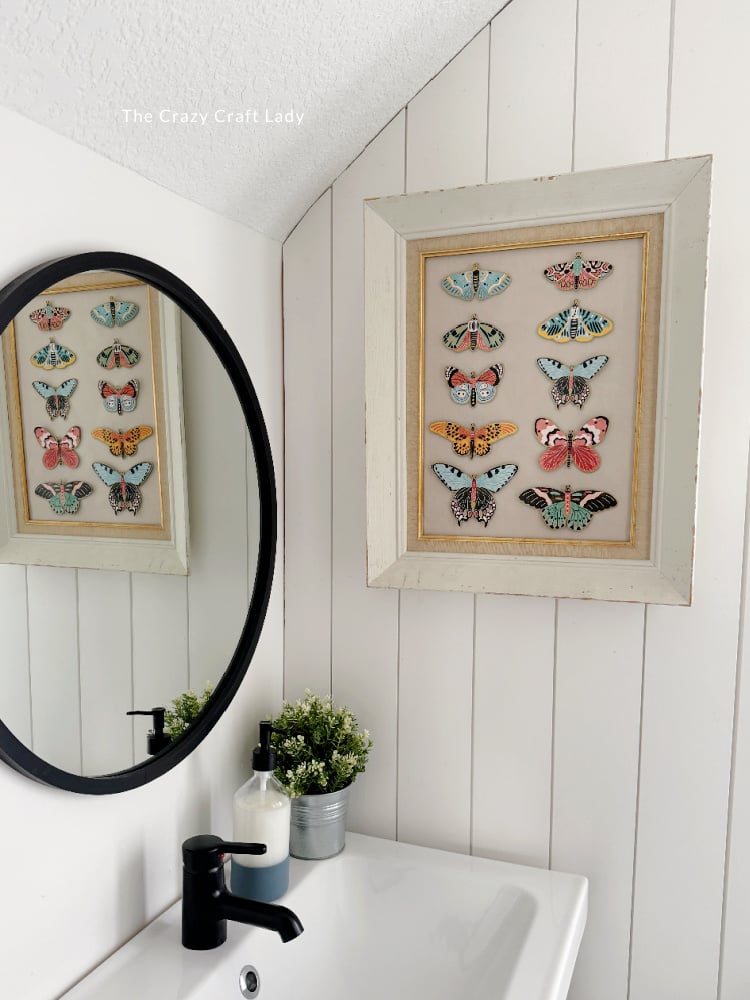 DIY dollar tree picture frame with butterfly stickers arranged inside to make butterfly wall art.