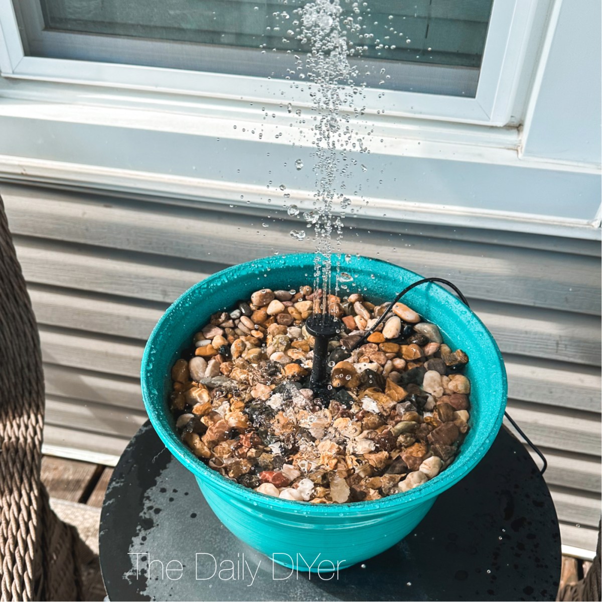 diy dollar tree craft of a teal flower pot filled with rocks and a fountain pump
